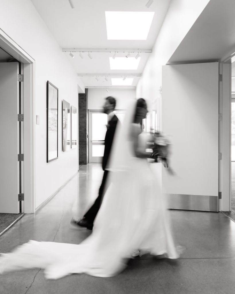 A bride and groom walking in an art gallery