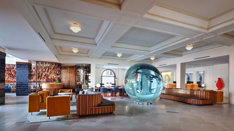 Large hotel lobby space with glass orb, leather coaches, check-in desk, and more