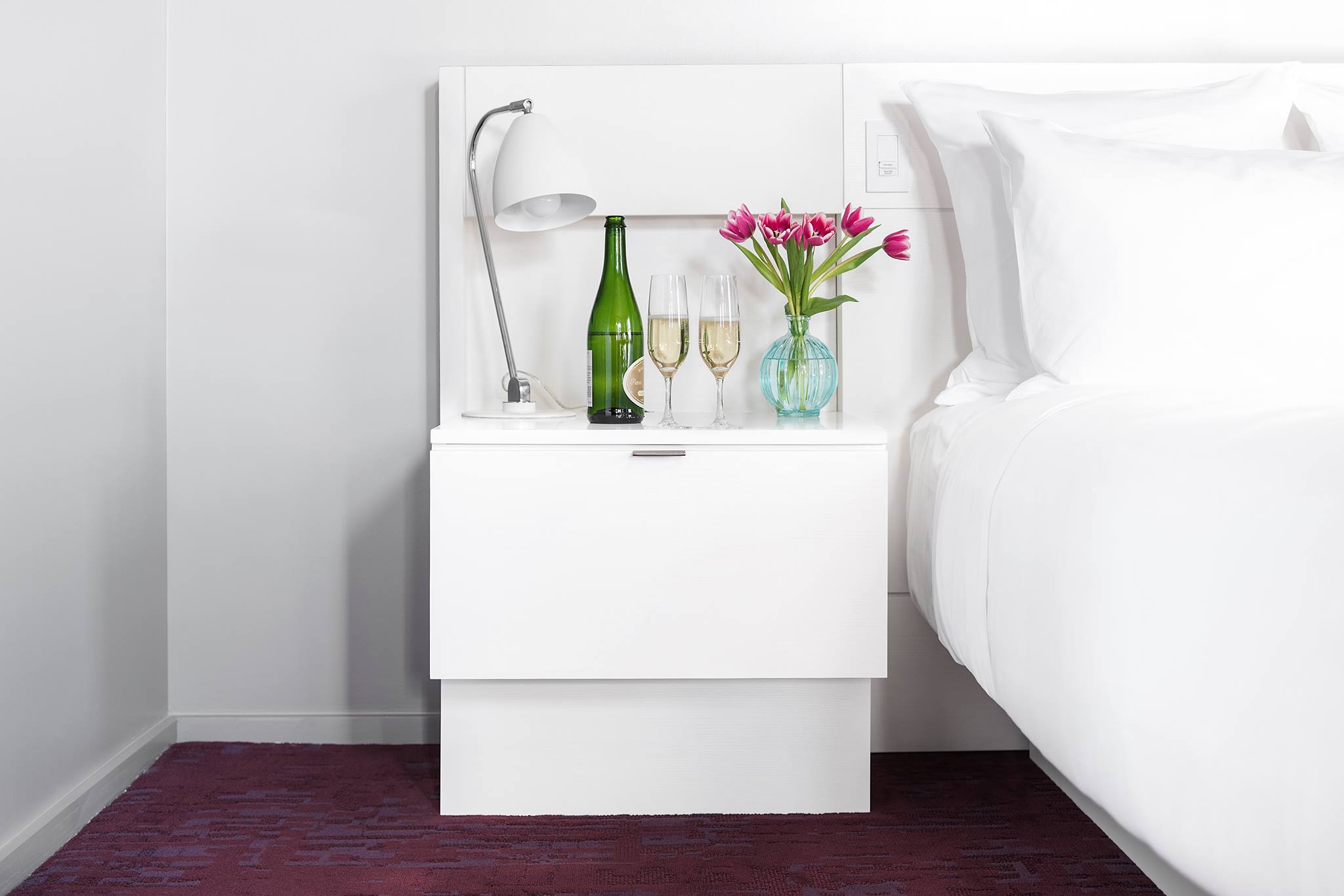 City Queen Room at 21c Lexington, bed and a side table topped with champagne and flowers.