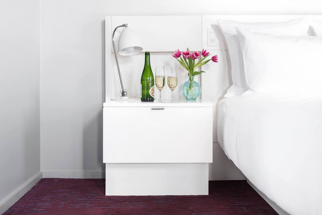 City Queen Room at 21c Lexington, bed and a side table topped with champagne and flowers.