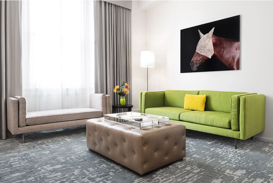 Green sofa, grey tufted ottoman, and cream bench near a window