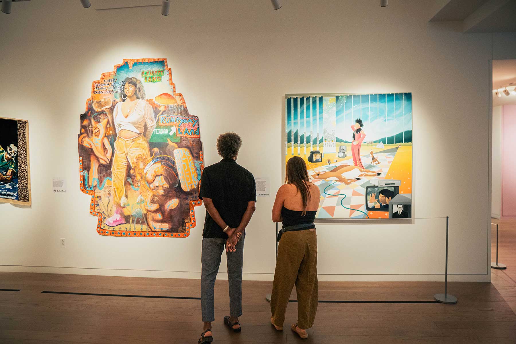 Two people looking at colorful artworks in the "Dress Up, Speak Up" exhibition at 21c Museum Hotel St. Louis