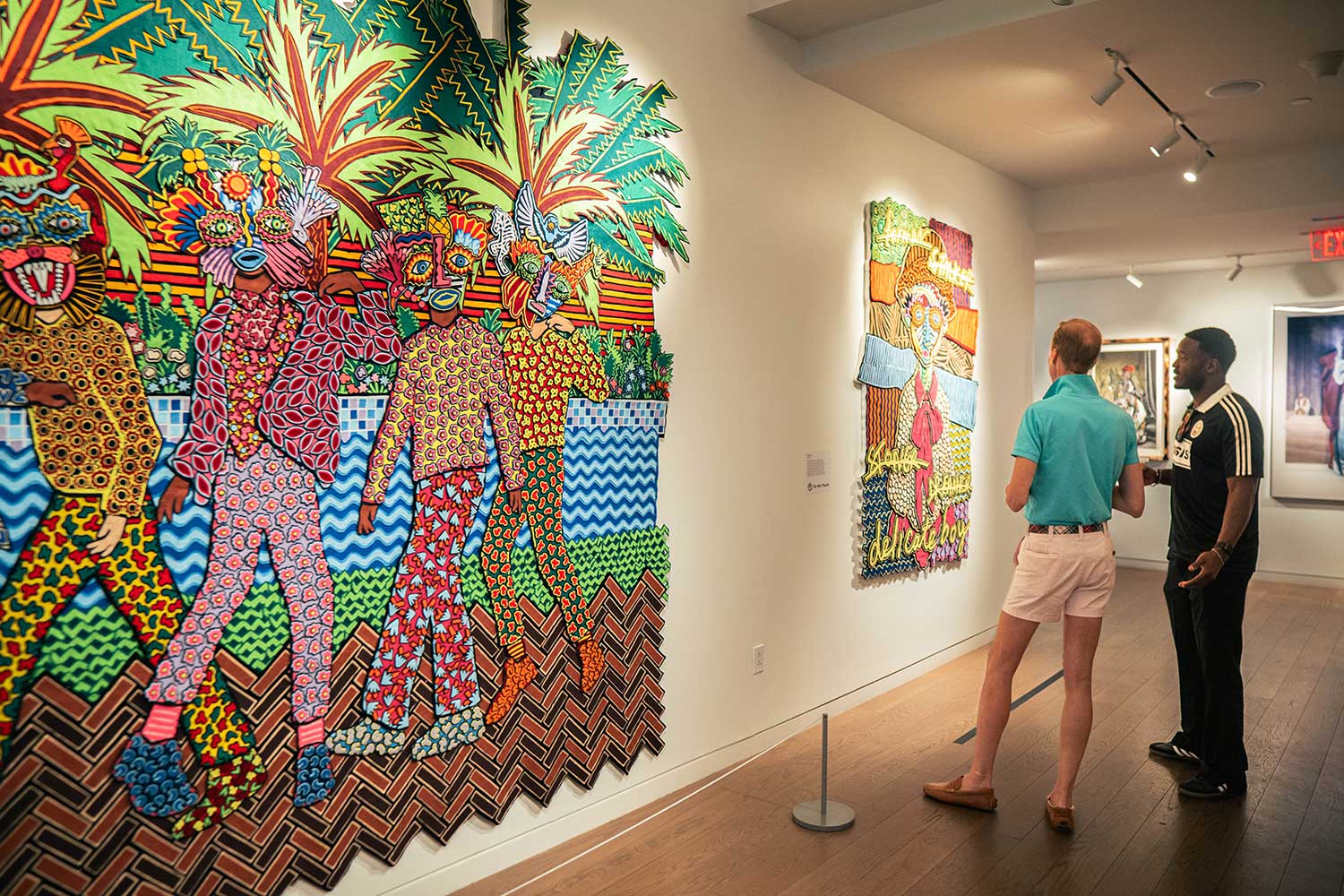 Two men looking at colorful artworks in the "Dress Up, Speak Up" exhibition at 21c Museum Hotel St. Louis