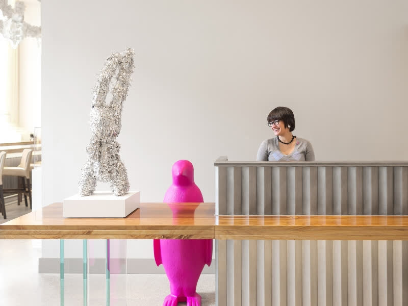 Hotel lobby front desk with woman and pink penguin behind it