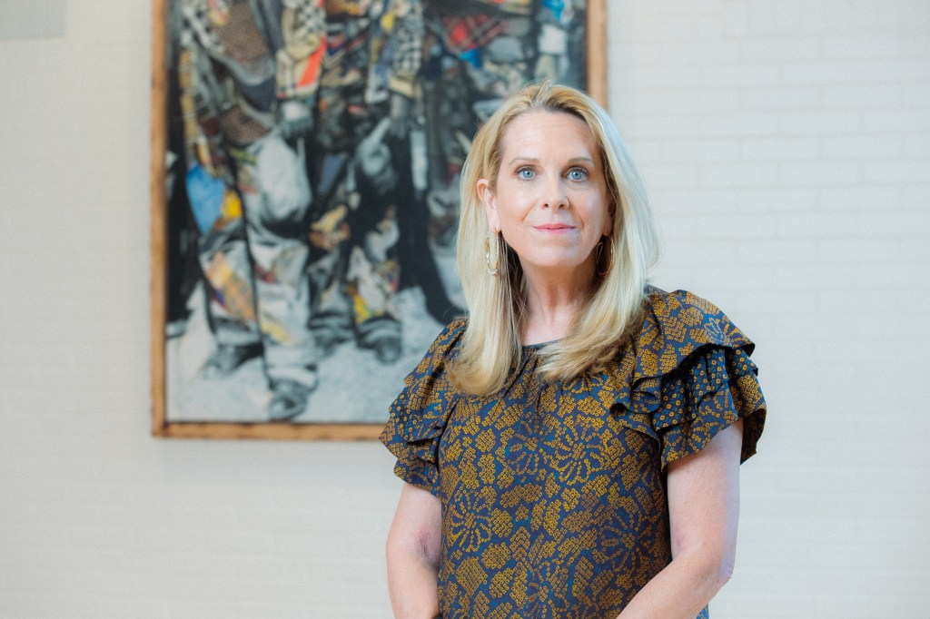 Woman in front of art work poses and looks at the camera