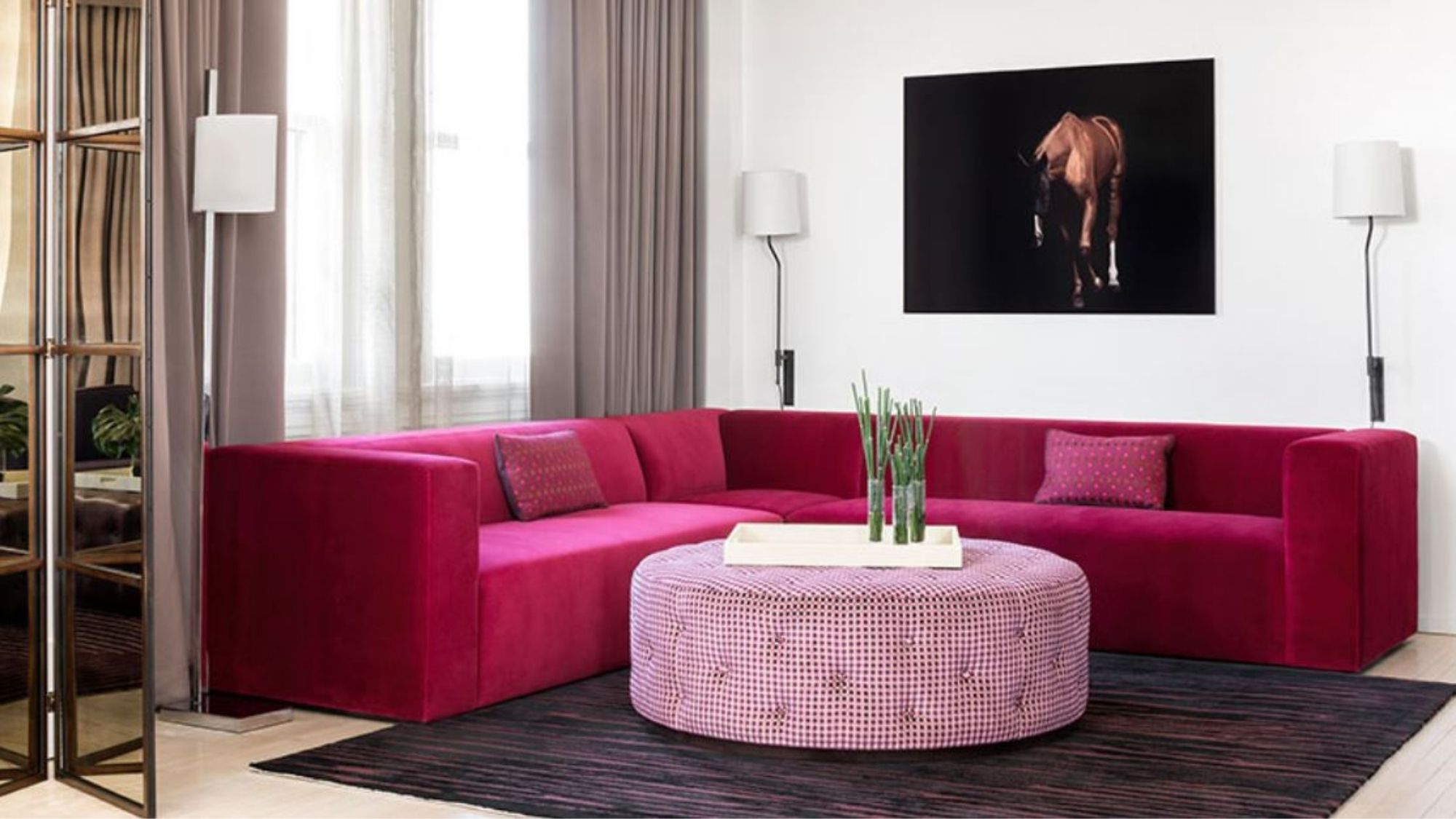 Hotel room living area with bright pink couch, coffee table and art on the wall