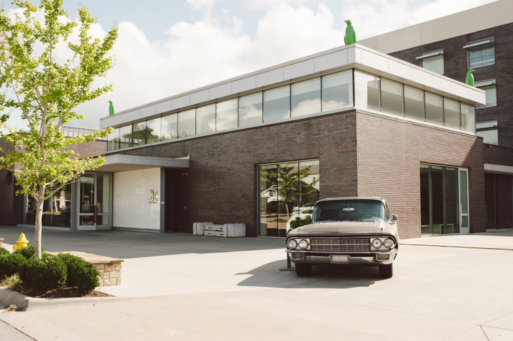 Exterior of a modern hotel with a penguin on the roof and a car out front