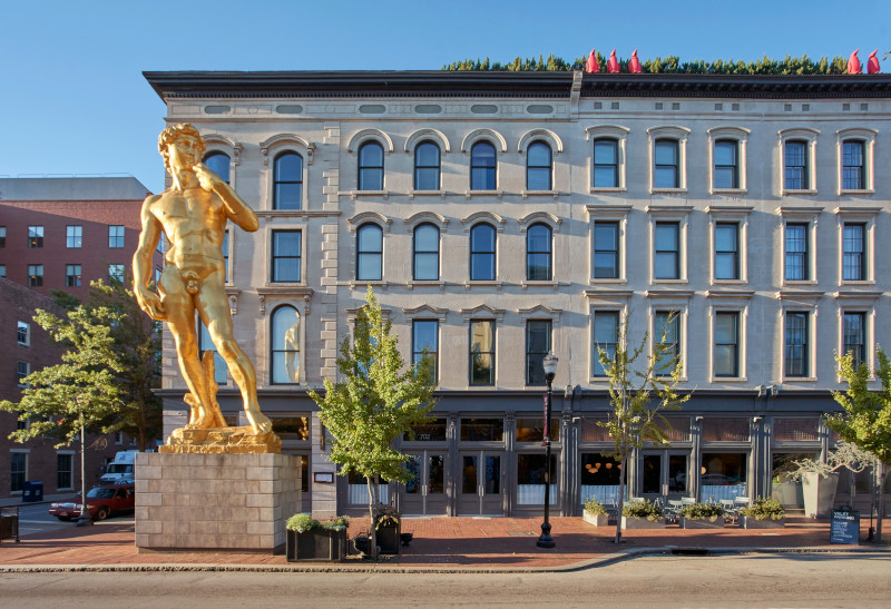Exterior of a large building with a gold statue of The David outside