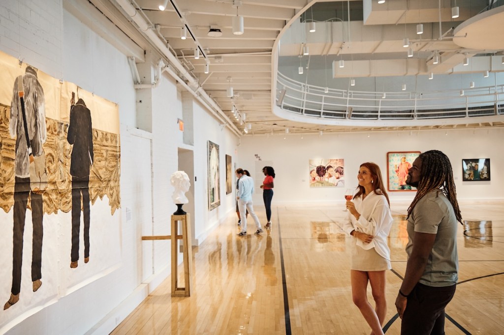Gallery space filled with art with man and woman looking at art