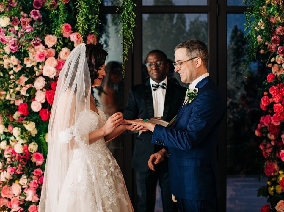 Man and women saying vows in front of floral backdrop at 21c Louisville.