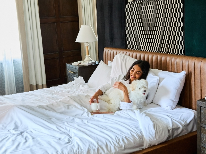 woman in bed with fluffy white dog