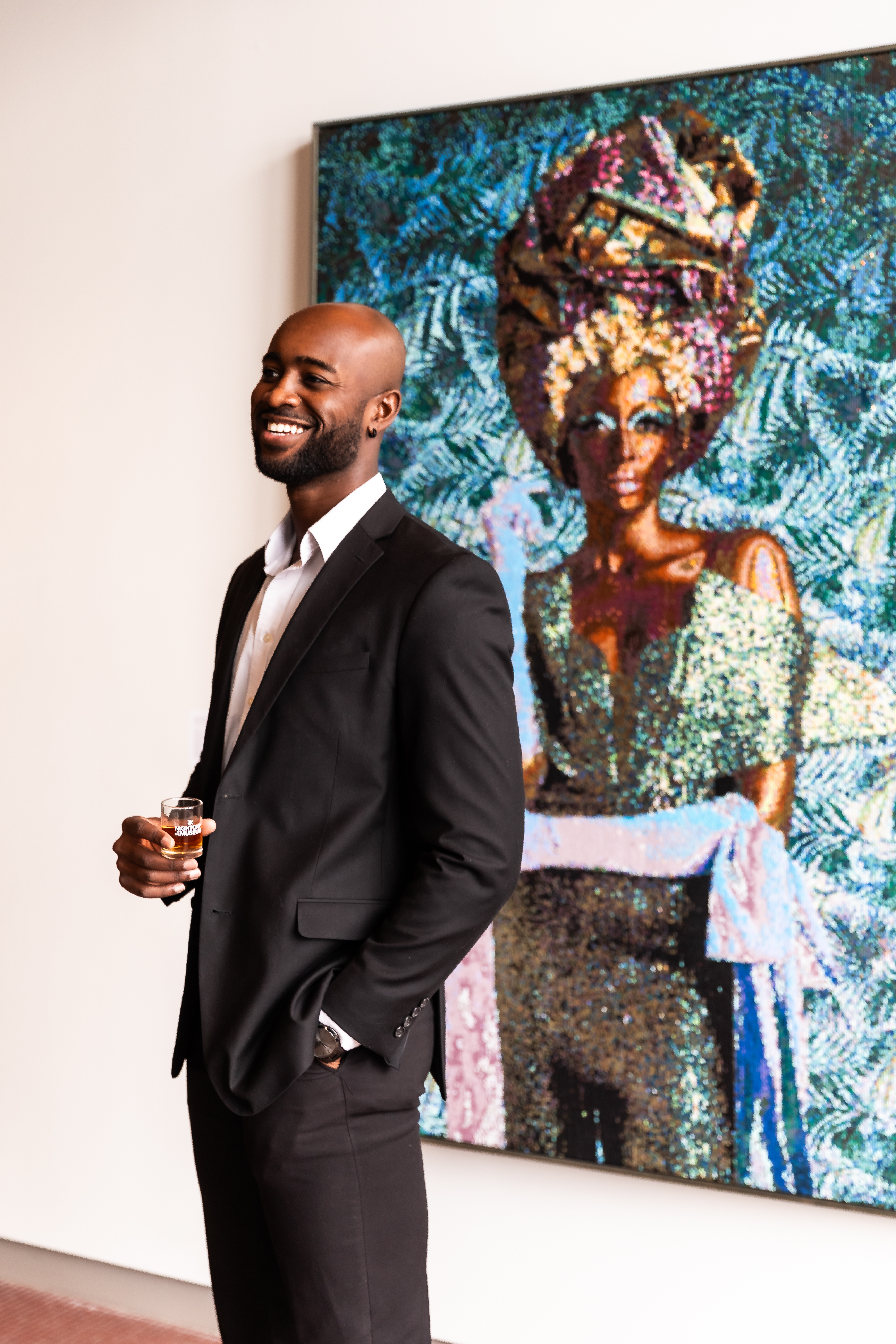 Man standing in front of artwork at 21c Museum Hotel with Nightcap at the Museum in hand.