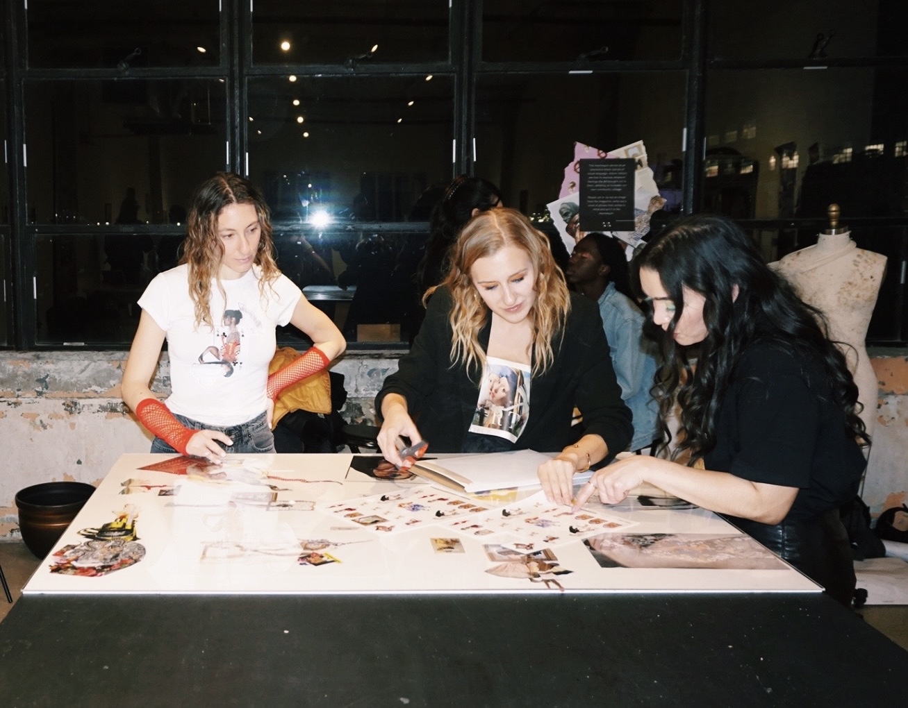 Group of women gathered around a table to look at images.