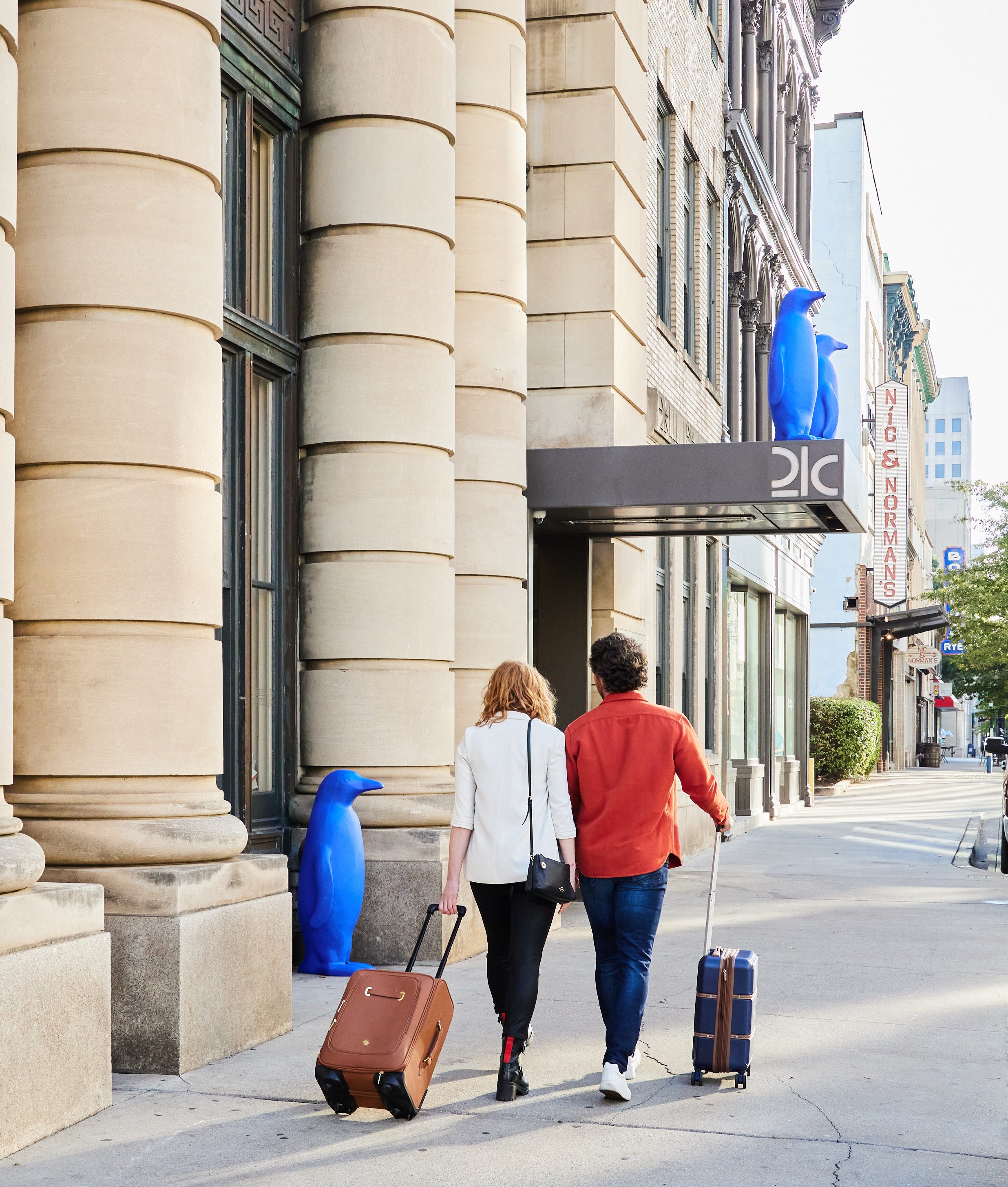 Man and Woman walking with Suitcases into 21c Museum Hotel Lexington.