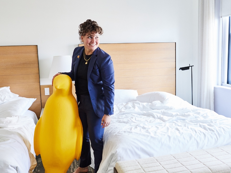 Person standing with yellow penguin statue in hotel room