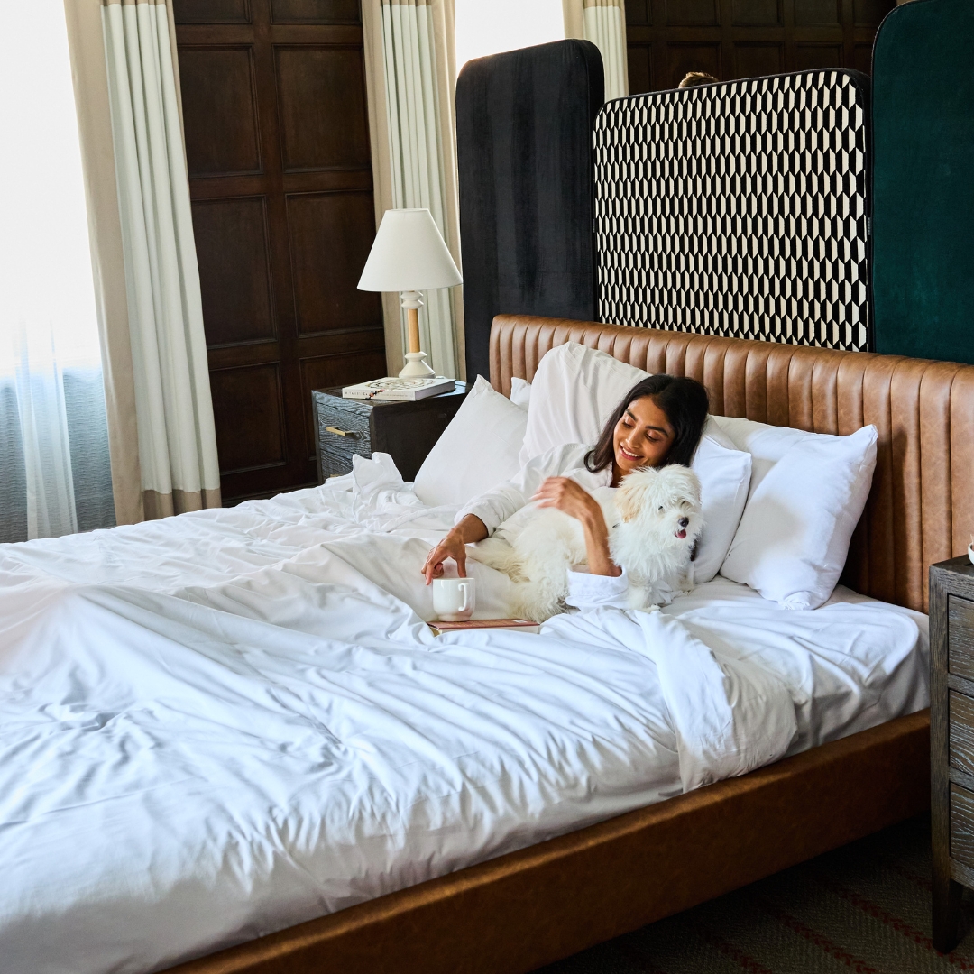 Girl in bed with white fluffy dog