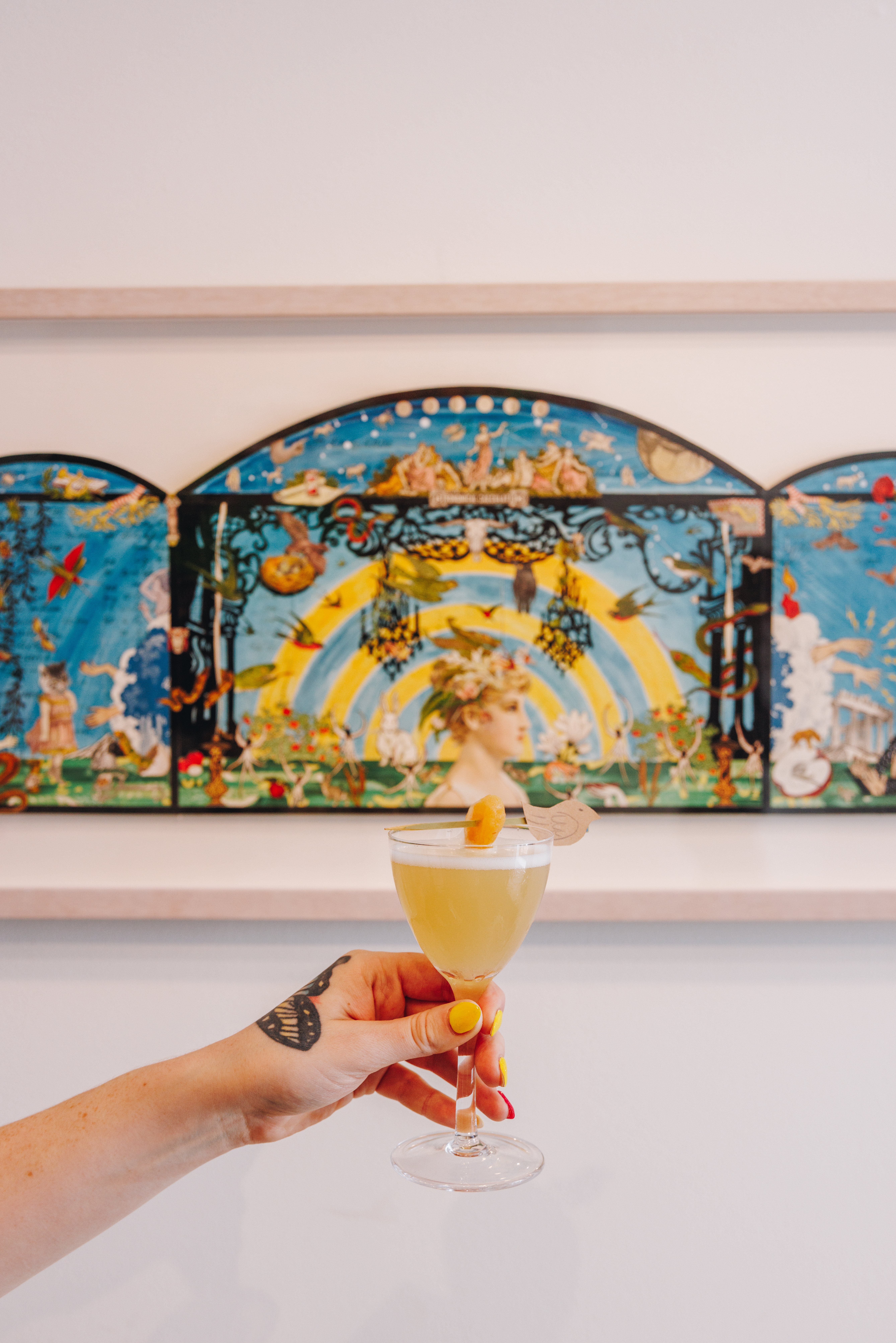 Hand Holding Cocktail in front of Artwork