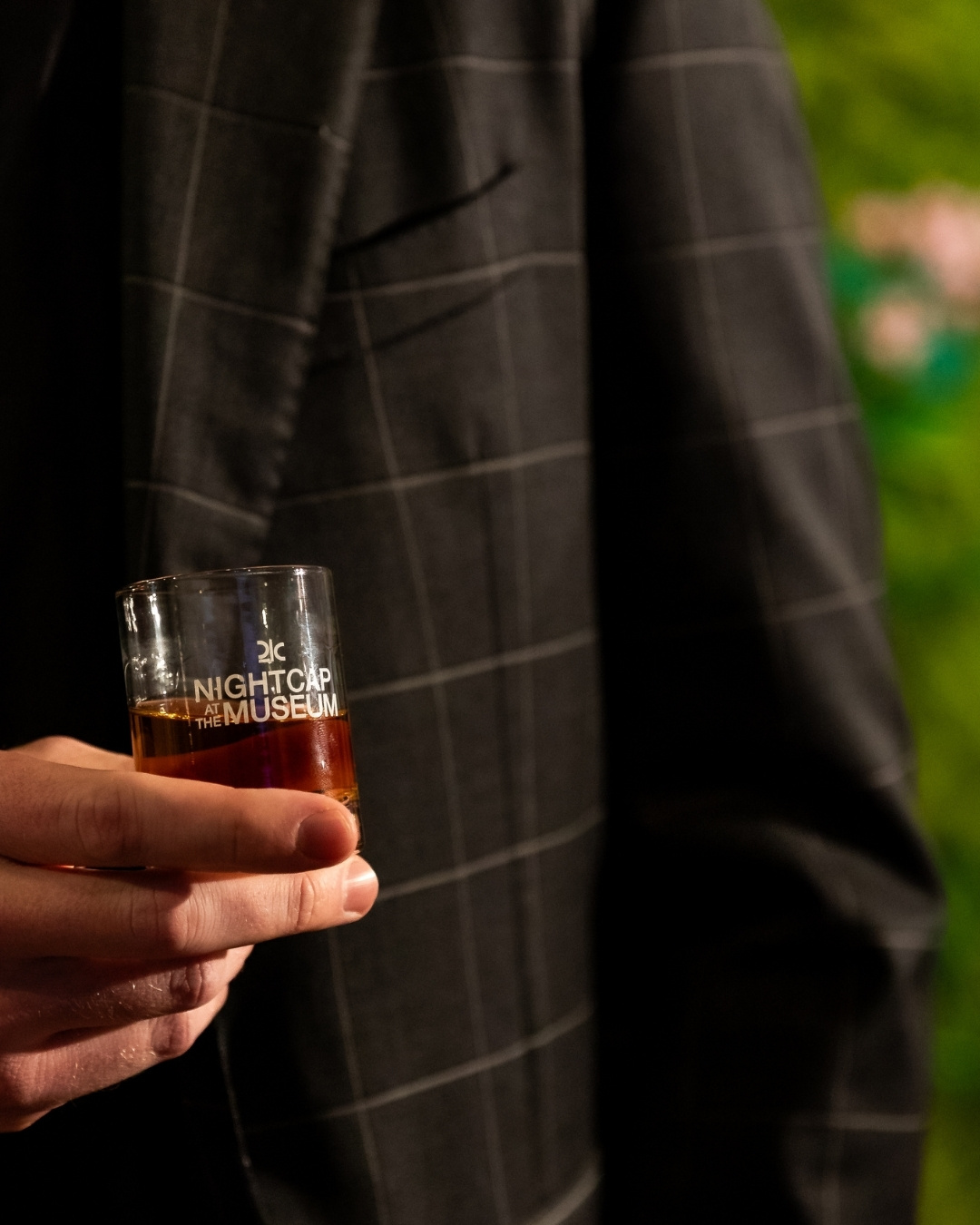 Close up image of a glass of bourbon held in a man's hand